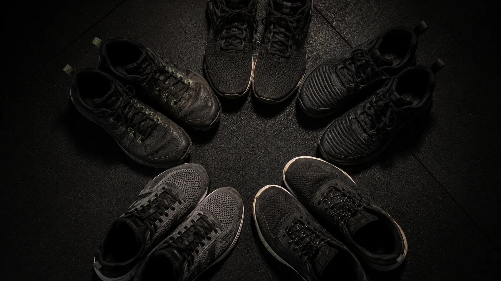 A small group of athletic shoes arranged in a circle on a gym floor, suggesting a group huddle without showing faces